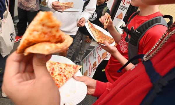 Young kids holding pizza slices on paper plates