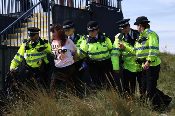 A Just Stop Oil protester is led away by police and security near the 17th hole during the second day of the British Open Golf Champio<em></em>nships at the Royal Liverpool Golf Club in Hoylake, England, on July 21, 2023.