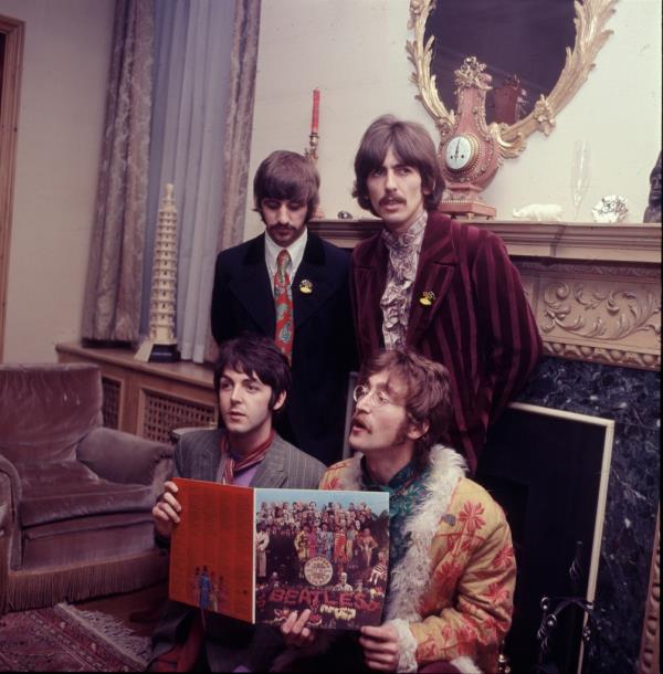 The Beatles pose with their album