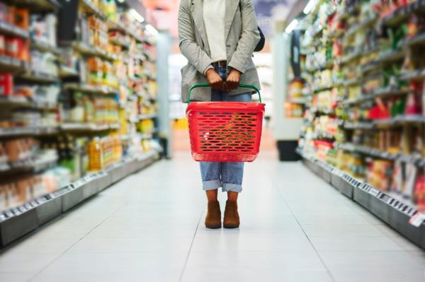 Supermarket aisle, woman legs and basket for shopping in grocery store.