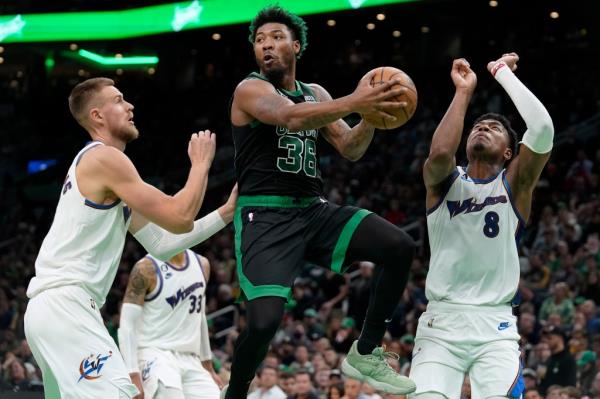 Boston Celtics guard Marcus Smart, center, looks to pass past Washington Wizards center Kristaps Porzingis, left, and forward Rui Hachimura, right, during the first half of an NBA basketball game Oct. 30, 2022