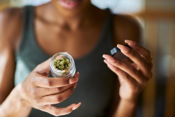 African American woman opening bottle of legal marijuana.