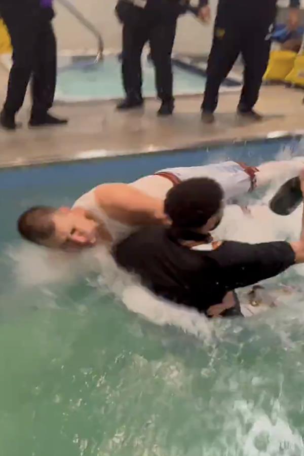 Nikola Jokic and Jamal Murray take a jump together into the pool, as Murray holds o<em></em>nto his champagne bottle. 
