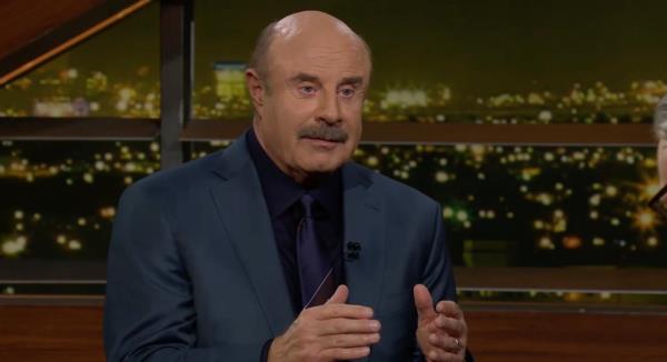 Phil McGraw in a suit participating in a debate with Bill Maher
