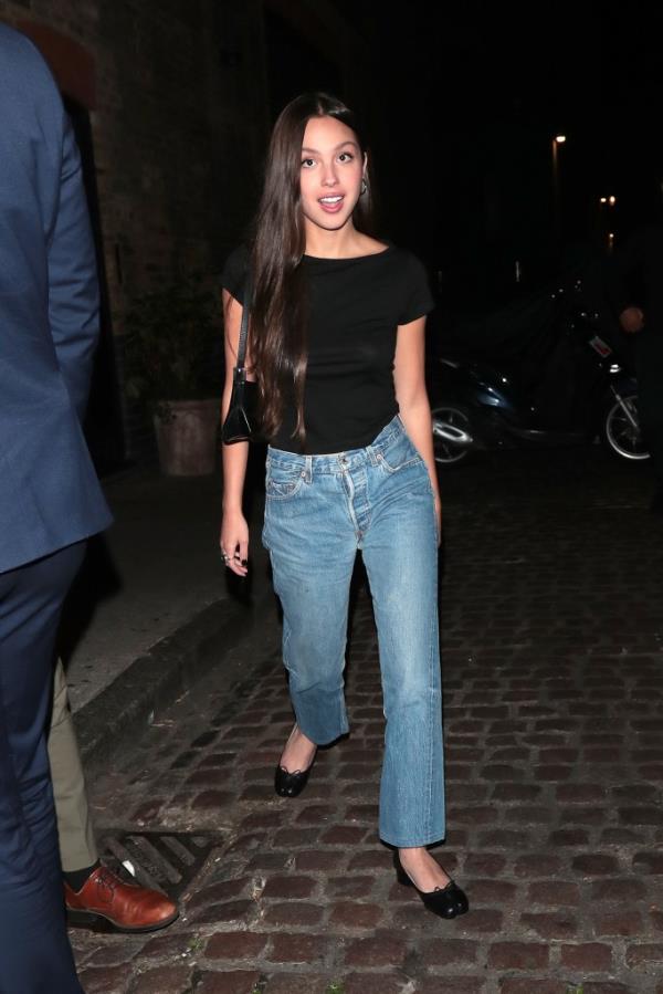 Photo of Olivia Rodrigo in jeans and a black shirt and ballet flats. 