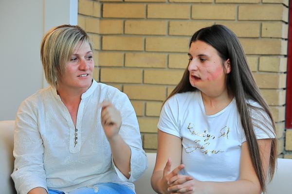 Older woman blo<em></em>nde white shirt talking to teenager daughters, white shirt dark brown hair and facial injury. 