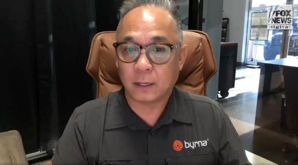 A man sitting in a chair during a Fox News interview with Byrna Technologies' Luan Pham