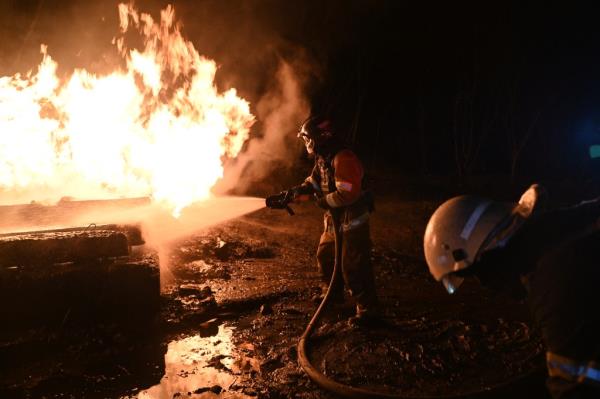 a firefighter spraying water on a fire in Kharkiv after a drone attack that killed seven people, including three children in Ukraine