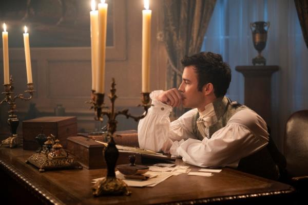 Benedict Bridgerton looking thoughtful sitting at a desk.