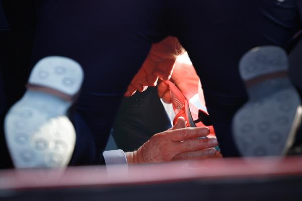 Secret Service agents assisting former President Do<em></em>nald Trump on stage at a campaign rally in Butler, Pennsylvania after he was grazed by a bullet