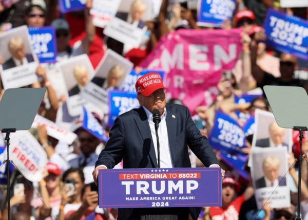 Former U.S. President Do<em></em>nald Trump in a suit and red hat, speaking at a campaign event in Chesapeake, Virginia