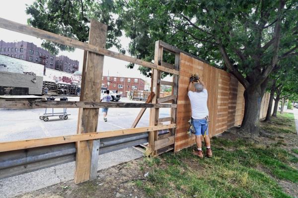 A man puts up part of wall around the lot to keep people out.