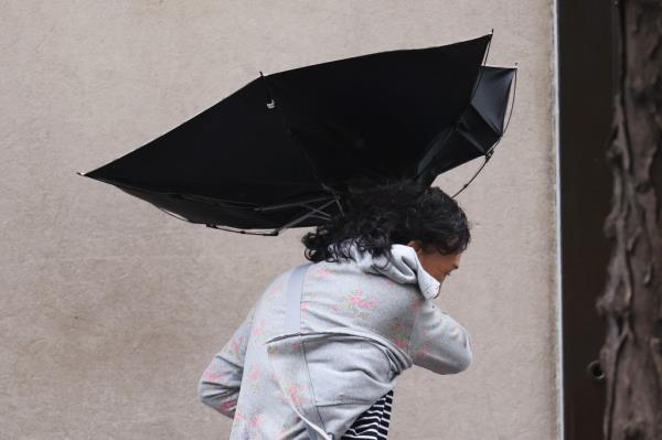 People using umbrellas to protect themselves from heavy wind and rain during a storm in New York City on August 09, 2024.
