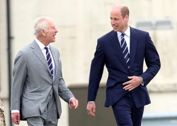 King Charles III and Prince William, dressed in suits, sharing a joke during the official handover of the role of co<em></em>lonel-in-Chief of the Army Air Corps.