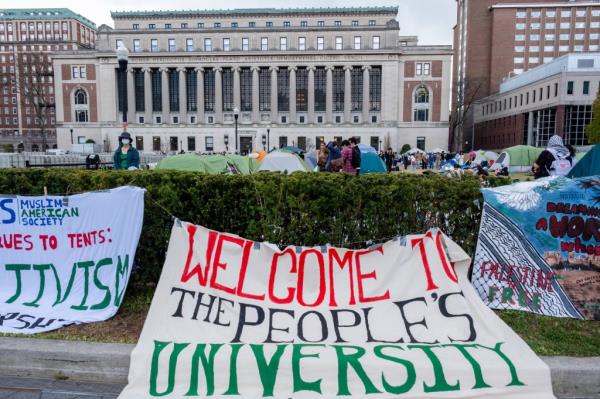 Banners hang on the hedge in front of the encampment in front of Butler Library at Columbia University.