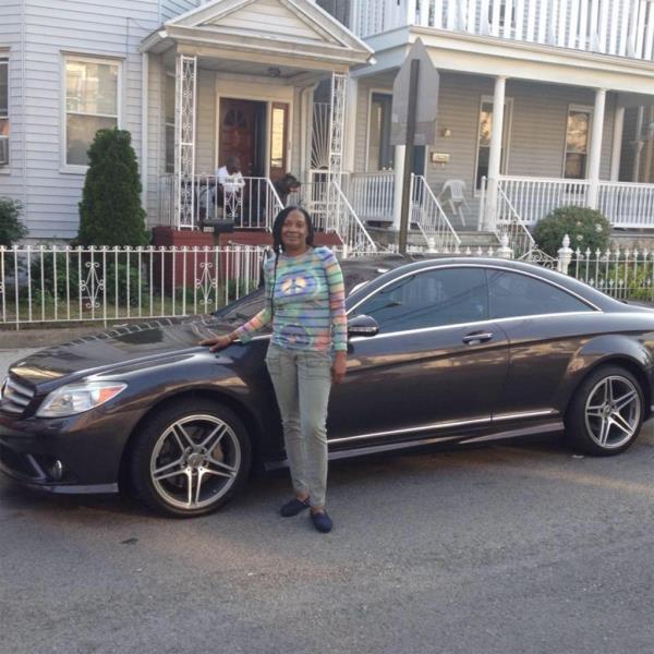 A woman in a peace sign shirt poses in front of her car and the home wher<em></em>e the incident took place.
