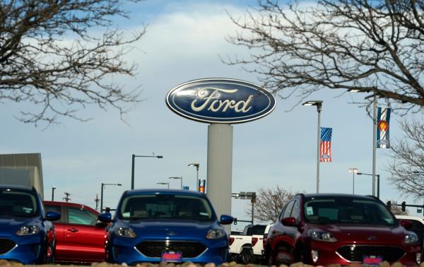 Several cars parked under a Ford sign at a dealership