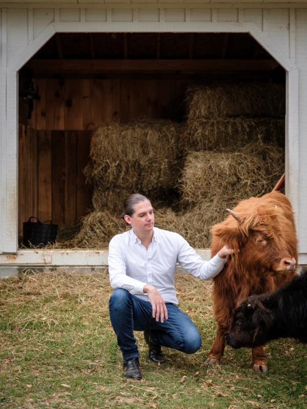 Robby Starbuck kneeling to pet a cow