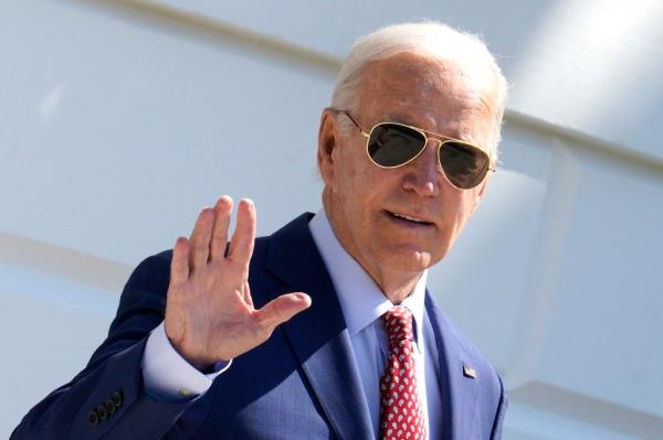 President Joe Biden waving to the media while exiting the White House, Washington, DC, dressed in a suit and sunglasses