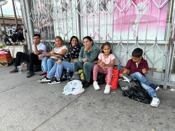 A Venezuelan migrant family sit outside a shop in El Paso, Texas, after entering the US.
