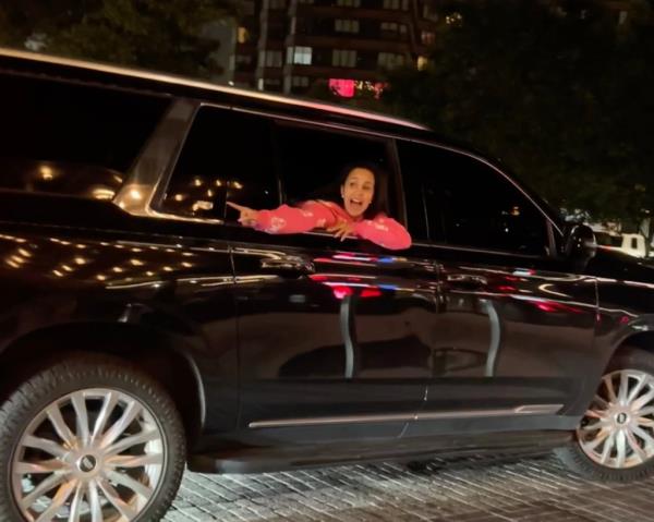 Cardi B is seen leaning from the window of a black SUV shouting