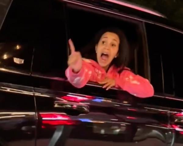 Cardi B is seen leaning from the window of a black SUV shouting