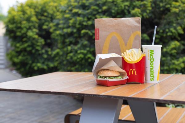 McDonald's burger, fries and soda on outdoor table.