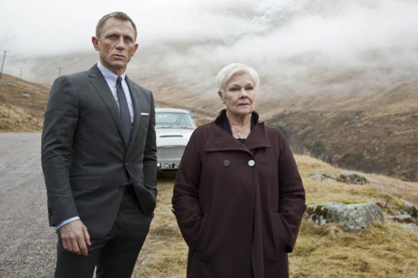 Actors Daniel Craig and Judi Dench standing in front of a car in a scene from the 2012 James Bond film, Skyfall