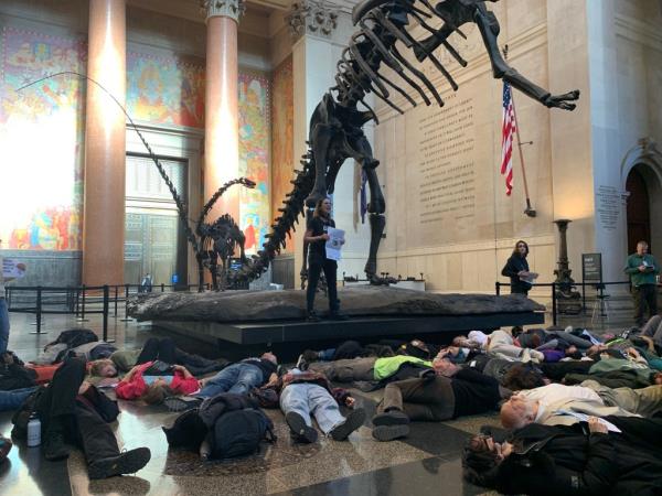 Climate protesters lay on the ground as speakers stood on the pedestal of the skeleton at the Museum of Natural History to speak a<em></em>bout the dangers of using fossil fuels on Sunday.