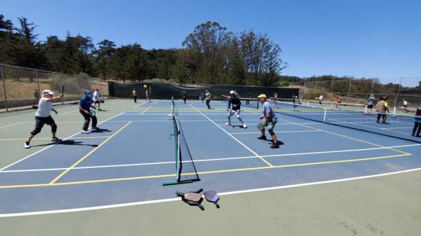 Wide shot of people playing pickleball on multiple courts in San Franciscos's Presidio. 