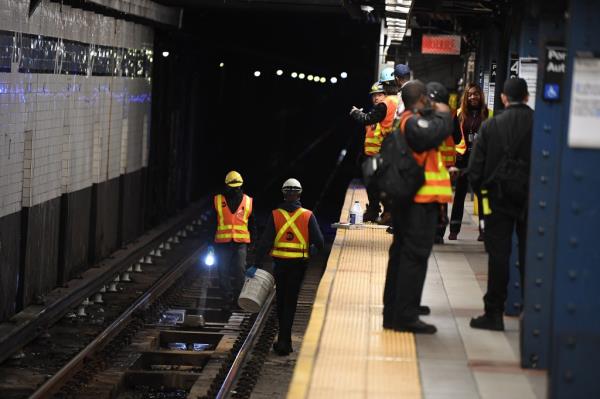 MTA workers inspect the tracks of the downtown ACE subway after a person was removed.