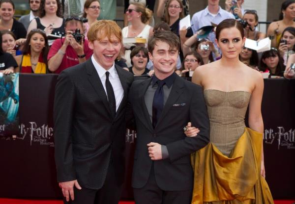 Rupert Grint, Daniel Radcliffe and Emma Watson smiling. 