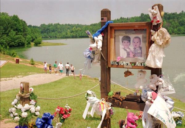 visitors walk down the ramp wher<em></em>e Alex and Michael Smith were drowned in a car in 1994 in Unio<em></em>n, S.C. A memorial for the boys is seen lakeside