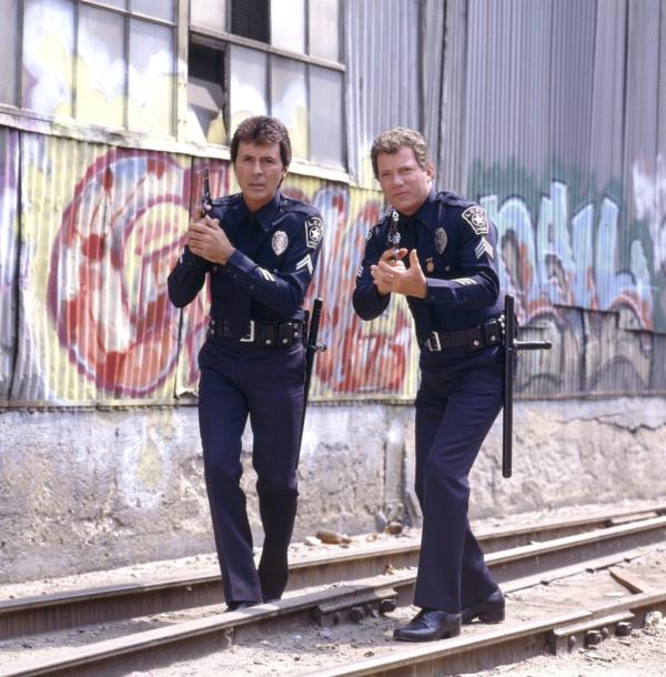 Actors James Darren and William Shatner portraying police officers in the CBS television drama 'T.J. Hooker', walking on train tracks in 1985.