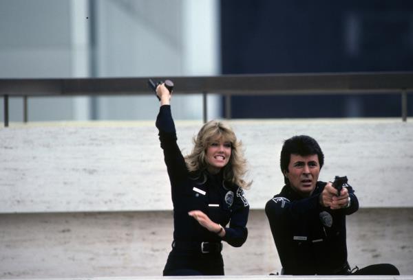 Actors Heather Locklear and James Darren, portraying their characters in the 1980s cop show 'T.J. Hooker', holding guns.