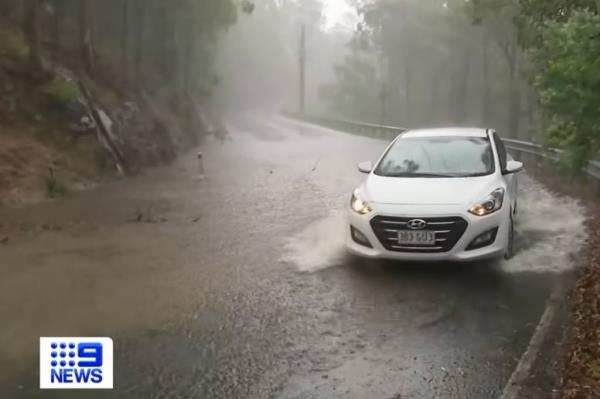 A car attempts to navigate through flooded waters during the deadly storm in that's left more than 90,000 households without power.