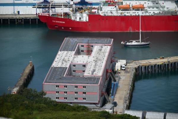 PORTLAND, ENGLAND - AUGUST 14: A yacht passes by the Bibby Stockholm immigration barge, on August 14, 2023 in Portland, England. More than three dozen migrants who arrived on the Bibby Stockholm barge last week have been temporarily relocated after traces of legio<em></em>nella bacteria were found in the barge's water supply. The Home Office has leased the barge to provide accommodation for asylum seekers and reduce its use of hotels. (Photo by Finnbarr Webster/Getty Images)