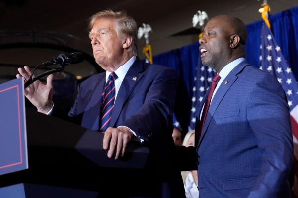 Do<em></em>nald Trump speaks as Sen. Tim Scott, R-S.C., stands next to him at a primary election night party in Nashua, N.H.
