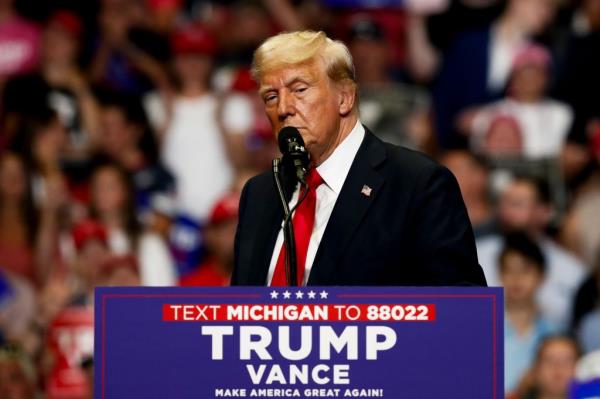 Former President Do<em></em>nald Trump speaking into a microphone at a campaign rally with running mate J.D. Vance at Van Andel Arena in Grand Rapids, 2024.