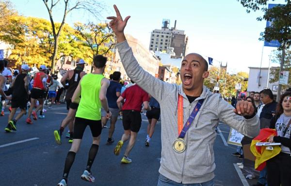 Yasser Ali, who ran the marathon last year, cheers on other runners near Layafette Avenue and Ashland Place, Brooklyn.