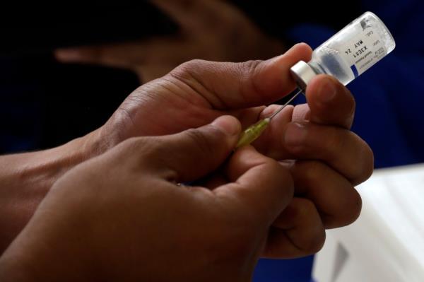 Vaccine shot is prepared in close-up shot of someone's hands.