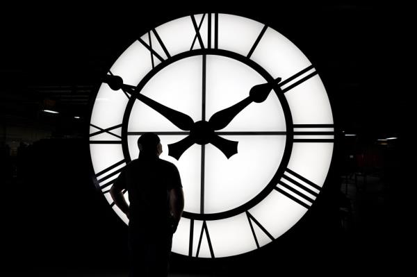 A large clock in front of a man who admires it.