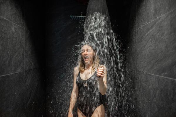 Woman hardening with bucket of ice cold water after hot sauna