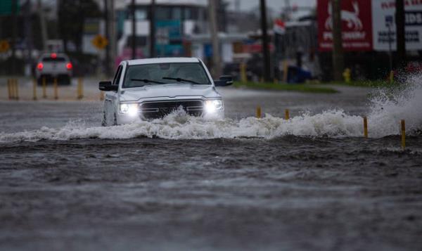 A car driving through a flood street in Fort Myers.