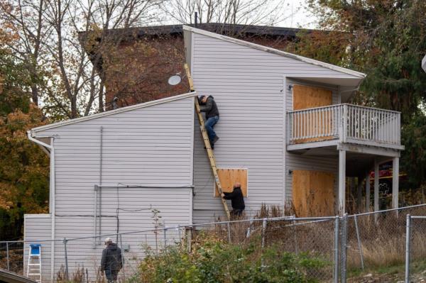 A worker climbs down a ladder after replacing the plywood that covers the upper windows of the house wher<em></em>e four University of Idaho students were murdered nearly a year ago. 