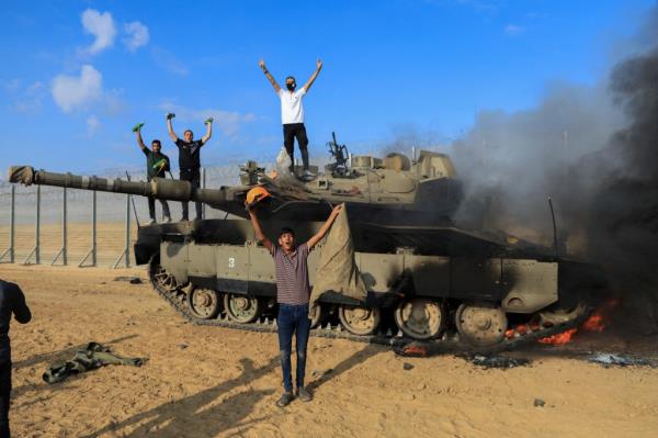 A Palestinian man takes a selfie in front of a burning Israeli military vehicle after it was hit by Palestinian gunmen who infiltrated areas of southern Israel on Oct. 7, 2023.