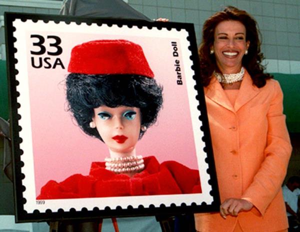 Jill Barad with a poster showing the USPS Barbie stamp