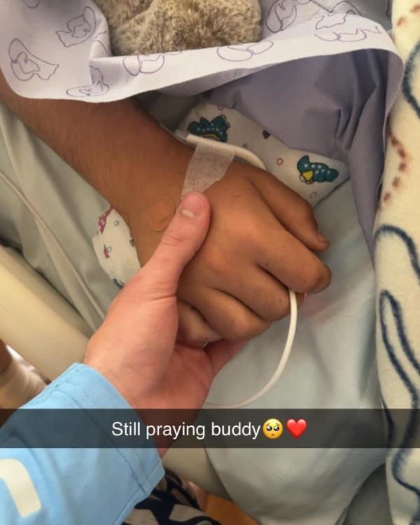 Mikey's hand being held in the hospital.
