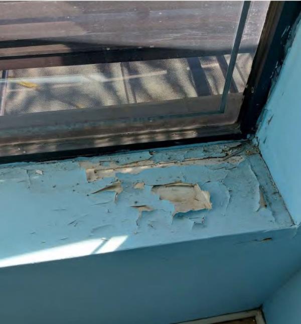Extensive water damage inside the apartment seen around blue windowsill.
