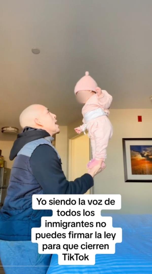 A man holding a baby up in the air, identified as migrant TikTok influencer Leo<em></em>nel Moreno from Columbus, Ohio